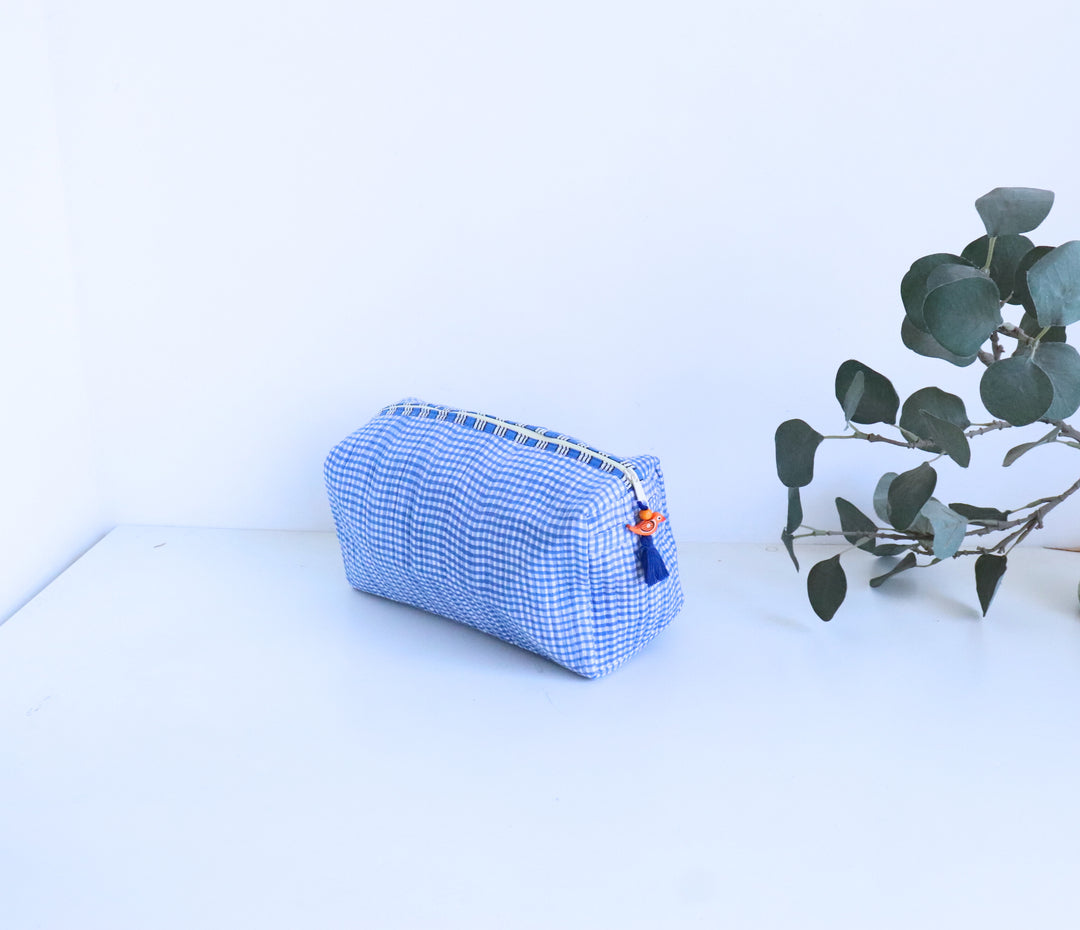Close-up of bead tassel zip detail on blue checks cosmetic pouch