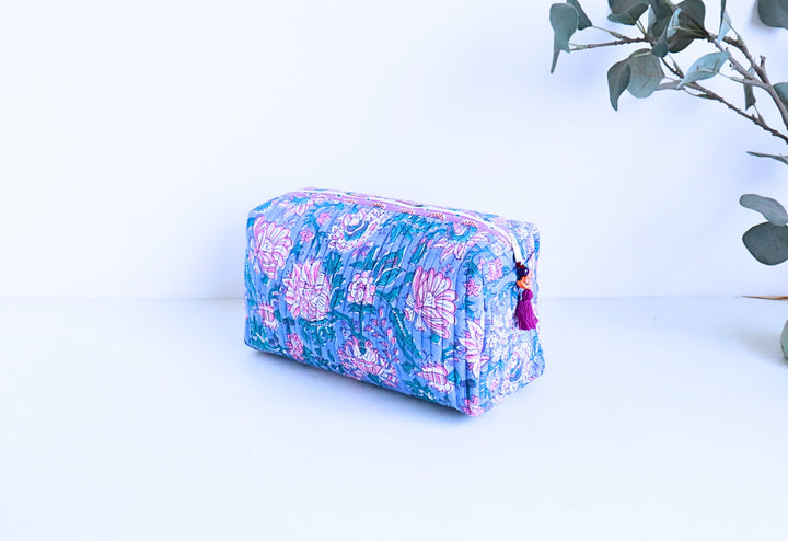 Close-up of bead tassel zip and block printed floral detail on blue and pink cosmetic pouch