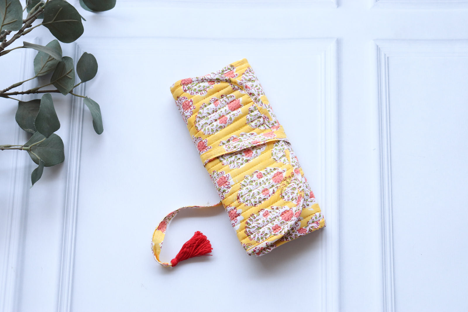 Personalized block print jewelry roll-up pouch with hand-embroidered name, unrolled to show compartments for rings, earrings,