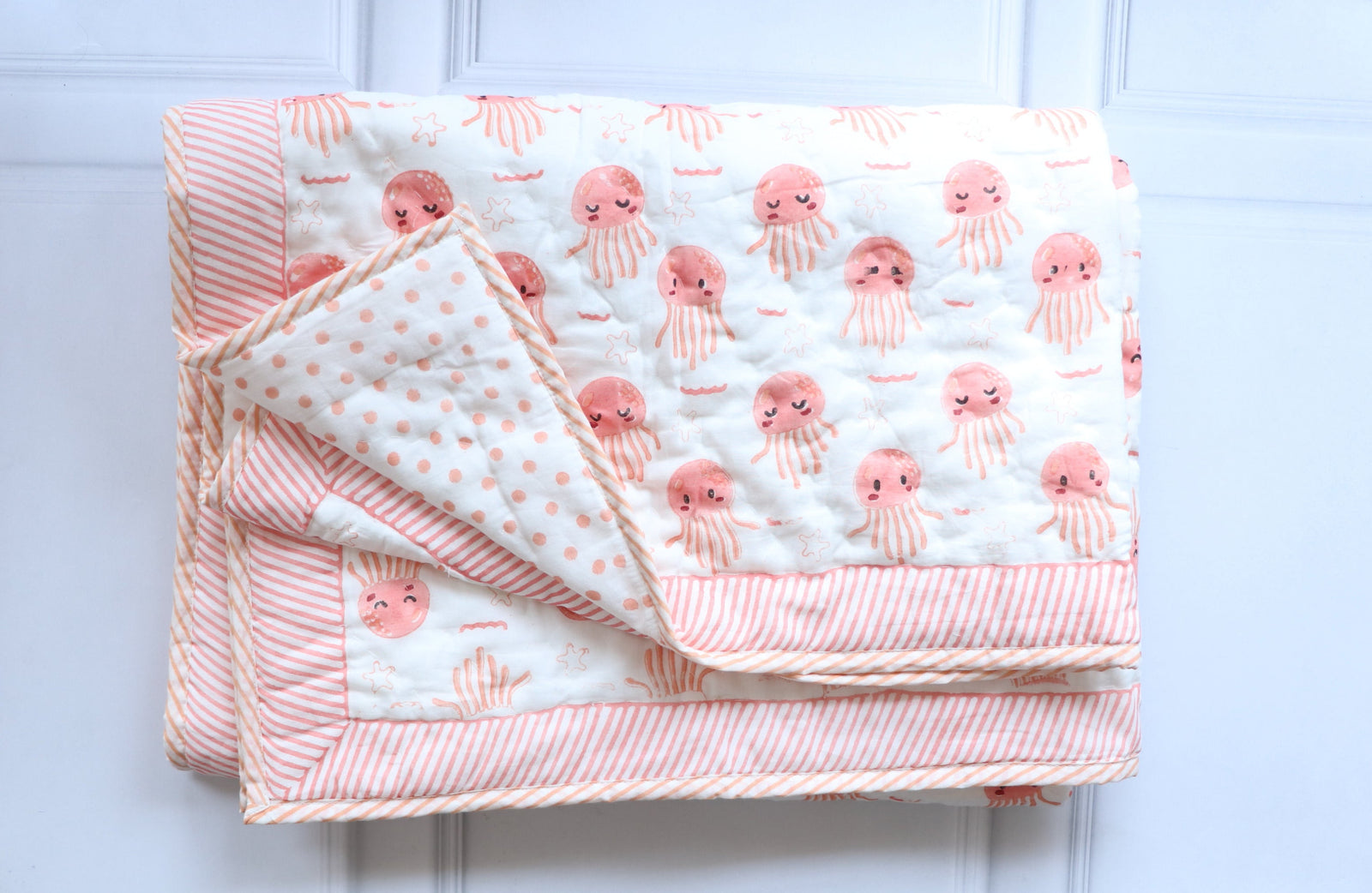 Close-up of pink octopus block print pattern and custom embroidered name on cotton baby quilt — Kari by Kriti