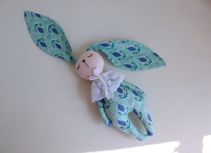 Hand block printed cotton bunny toy laying in a nursery setting, pink and turquoise