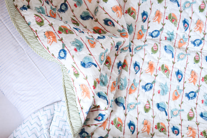 Flat lay of Cheerful Birdy kids quilt showing full print and personalized name detail
