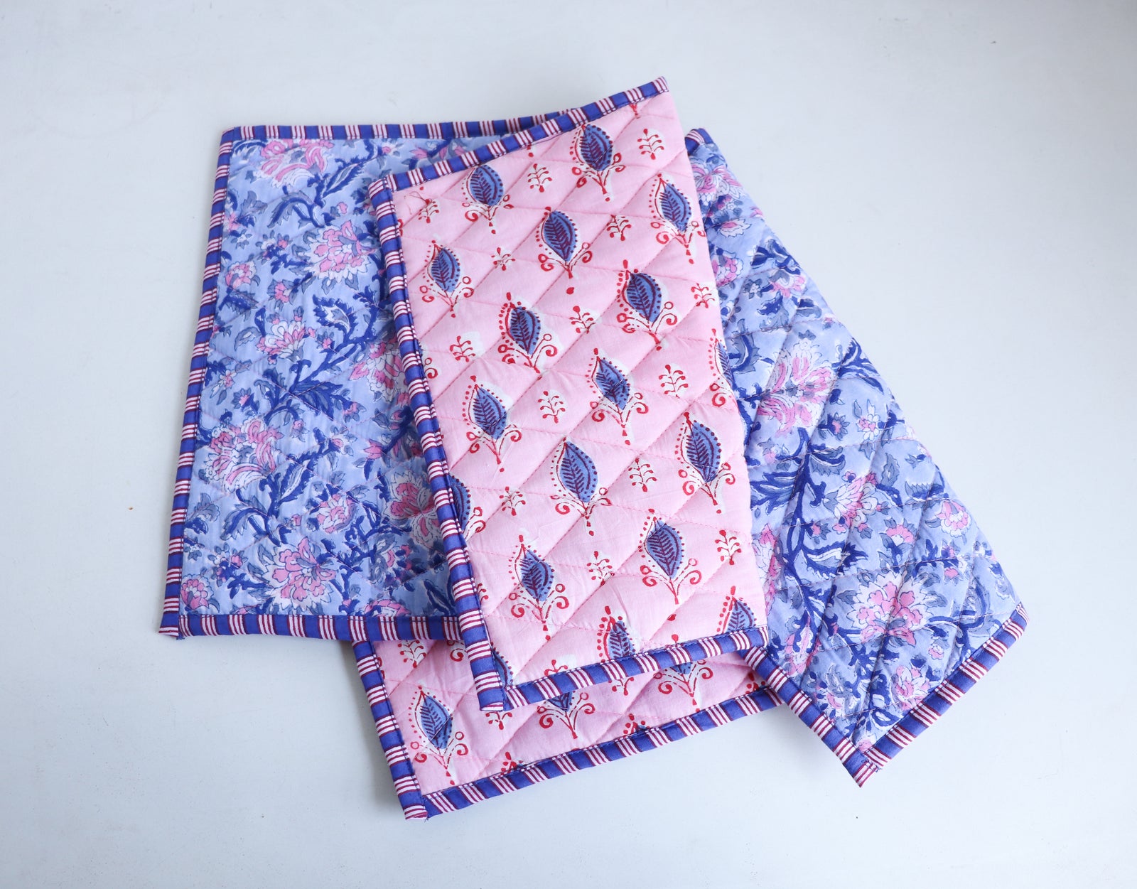 Reversible block print placemat in pink shown on dining table, quilted texture with artisanal Indian print