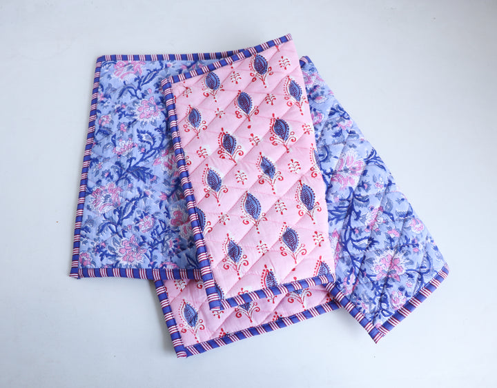 Reversible block print placemat in pink shown on dining table, quilted texture with artisanal Indian print