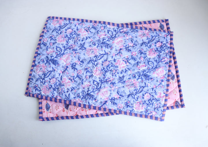 Set of 2 pink and blue reversible placemats styled on a dining table with matching block print table decor