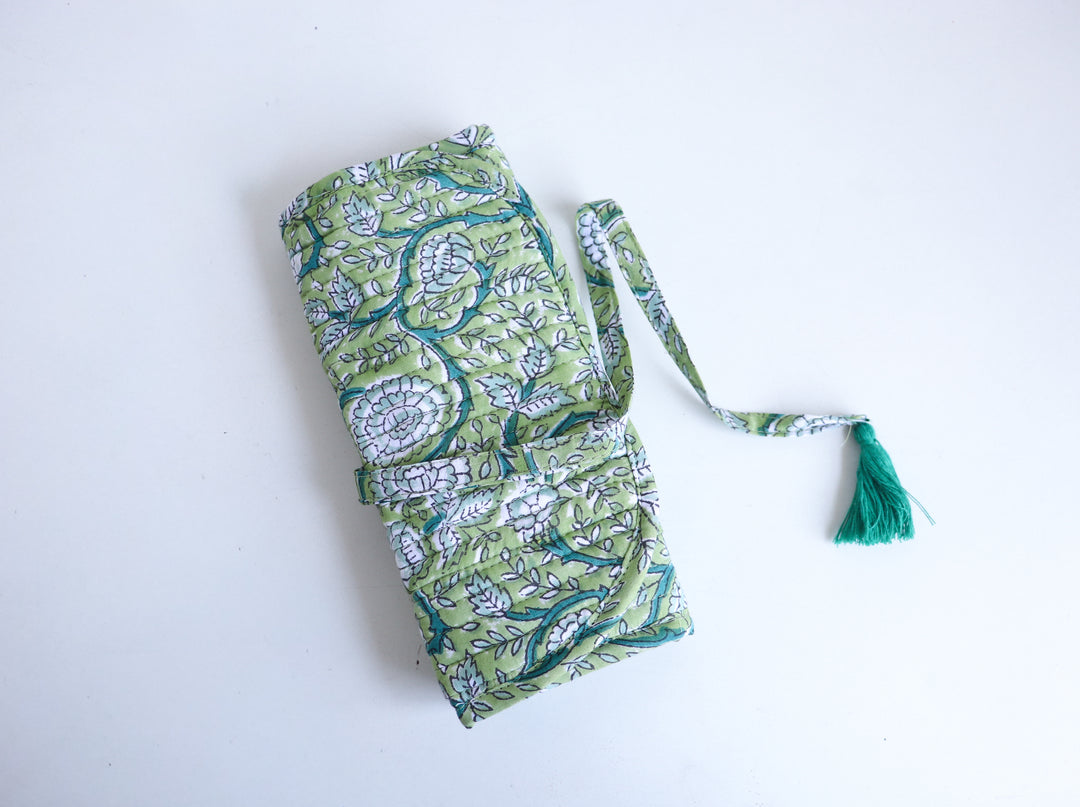 Personalized block print travel jewelry roll-up pouch with hand-embroidered name, unrolled to show compartments for rings, ea