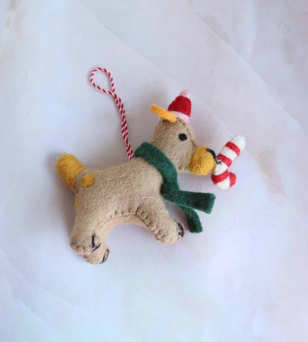 Brutus the Silliest handmade felt dog ornament in a green scarf holding a candy cane, front view