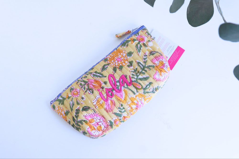 Floral pouch with pink text on a light blue background with green leaves.